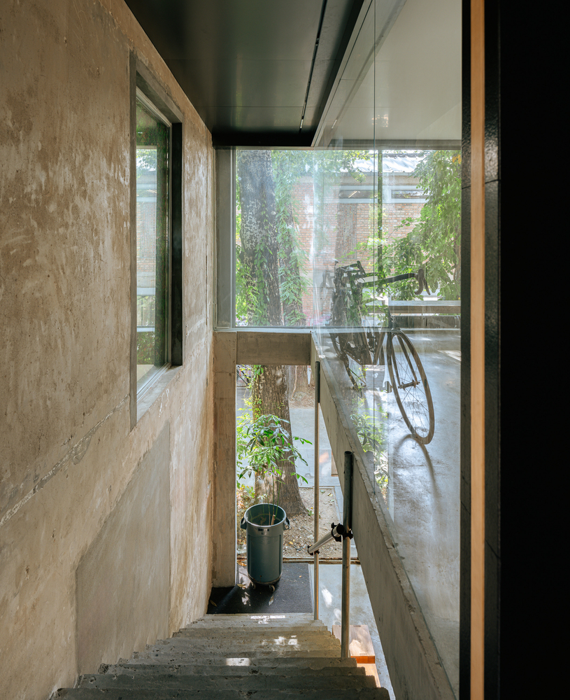 Narrow concrete stairwell with glass wall overlooking a bicycle in the courtyard below