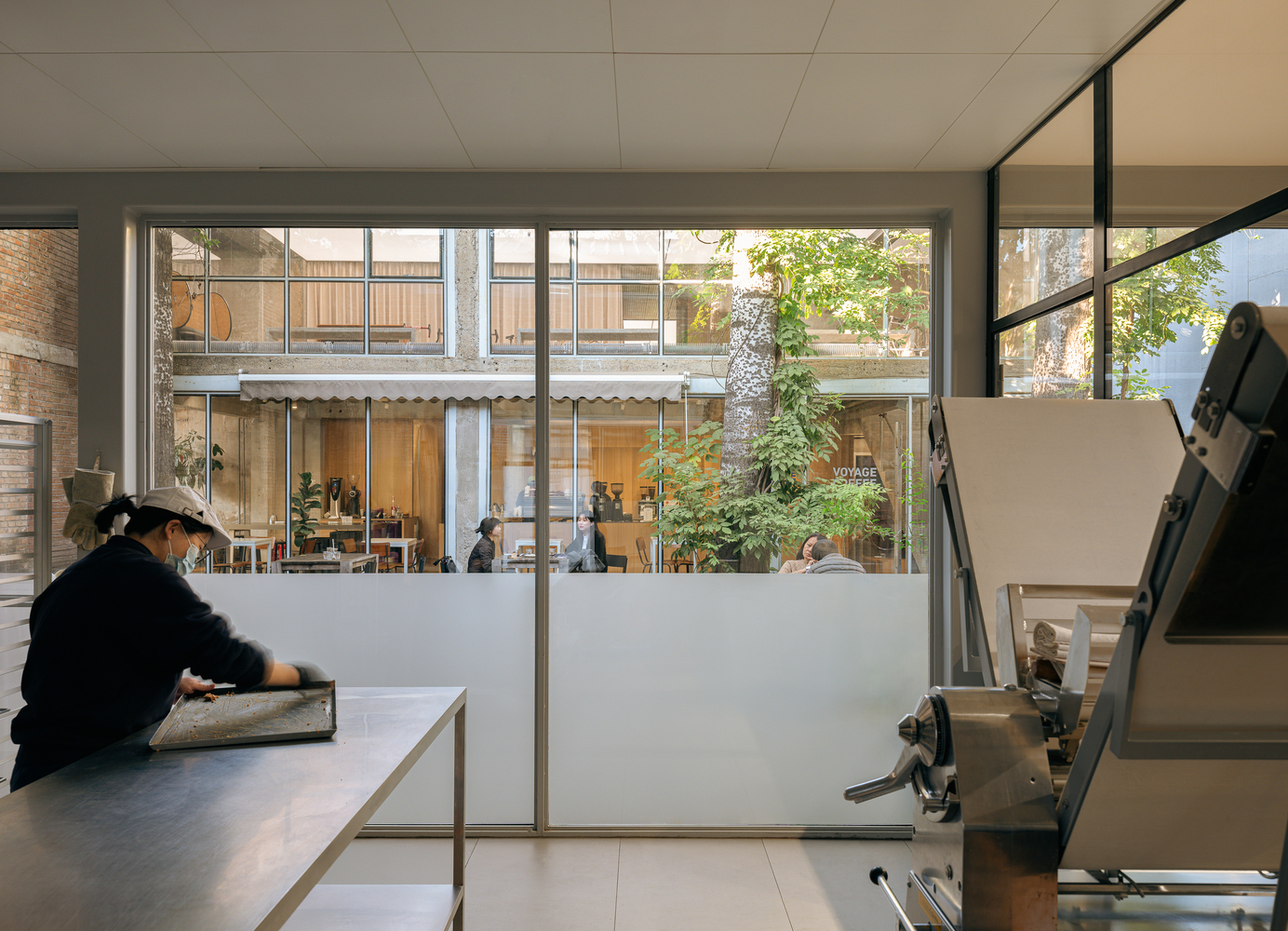 Studio space with printing press and view through glazed walls to a planted interior courtyard