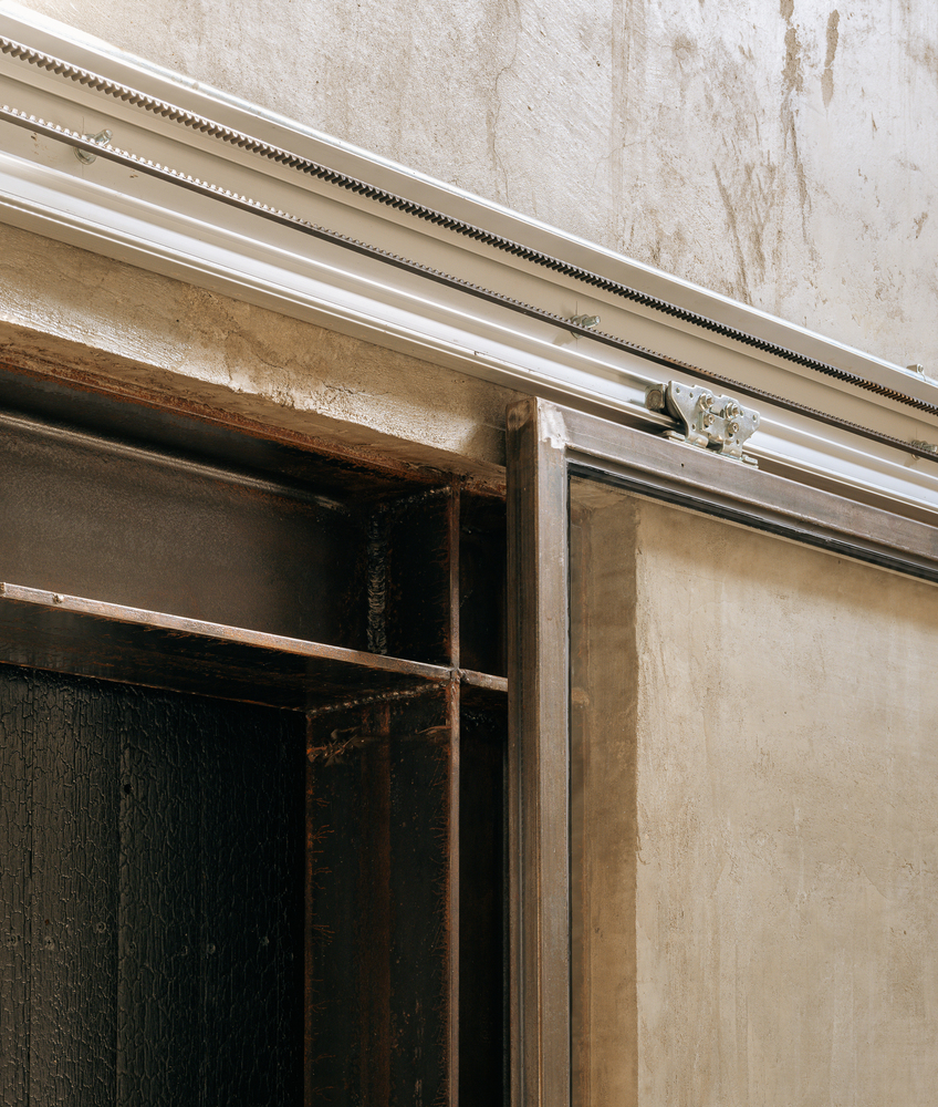Detail of sliding door track system with exposed timber beams and textured plaster wall