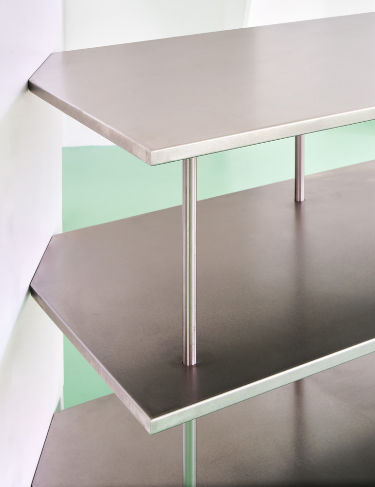 Stacked grey shelving with angled corners and mint green glass backsplash
