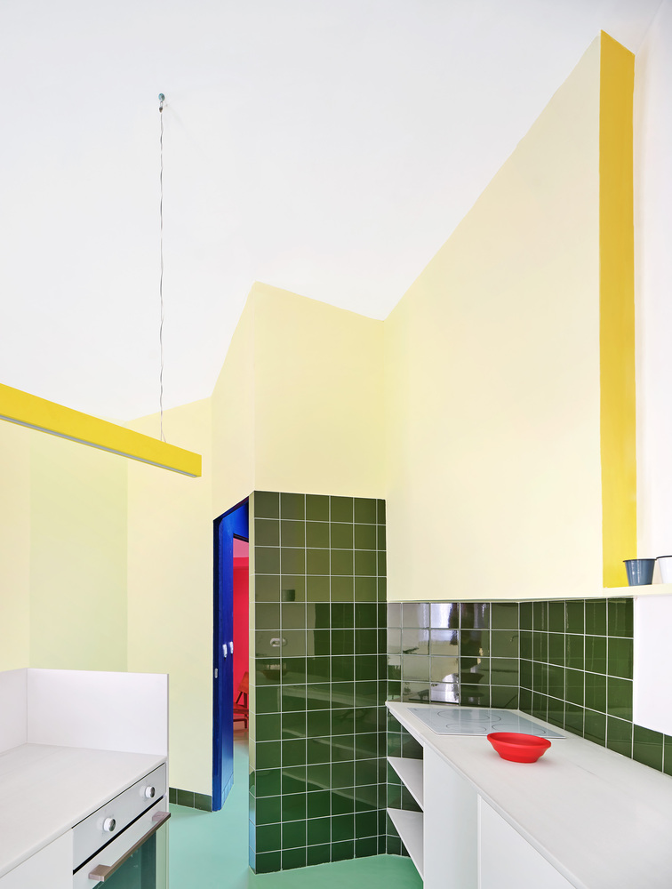 Kitchen counter with green square tile wall and yellow folded partition rising to the ceiling