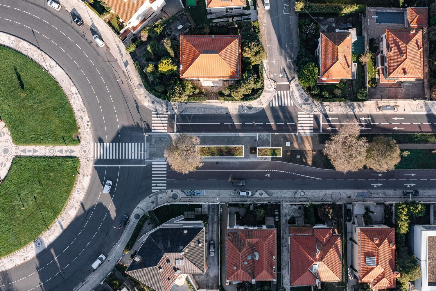 Drone view showing the roof canopy stretching across the roadway between residential buildings with terracotta tiles