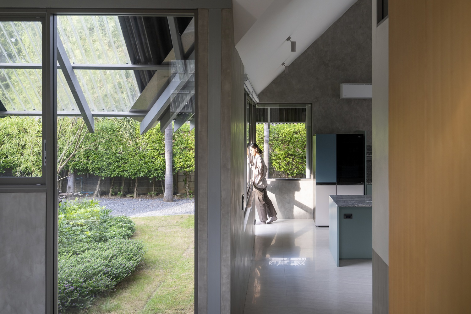 Hallway view through glazed doors opening to a lawn courtyard with bamboo screening