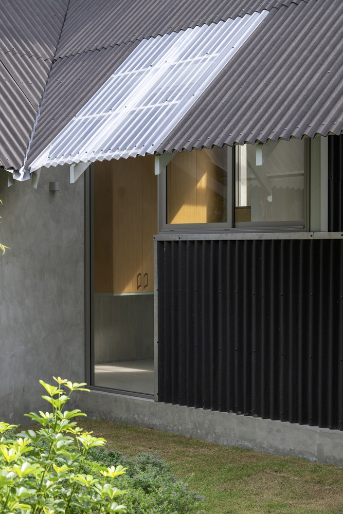 Courtyard view of corrugated metal cladding and translucent roof overhang with planted edge