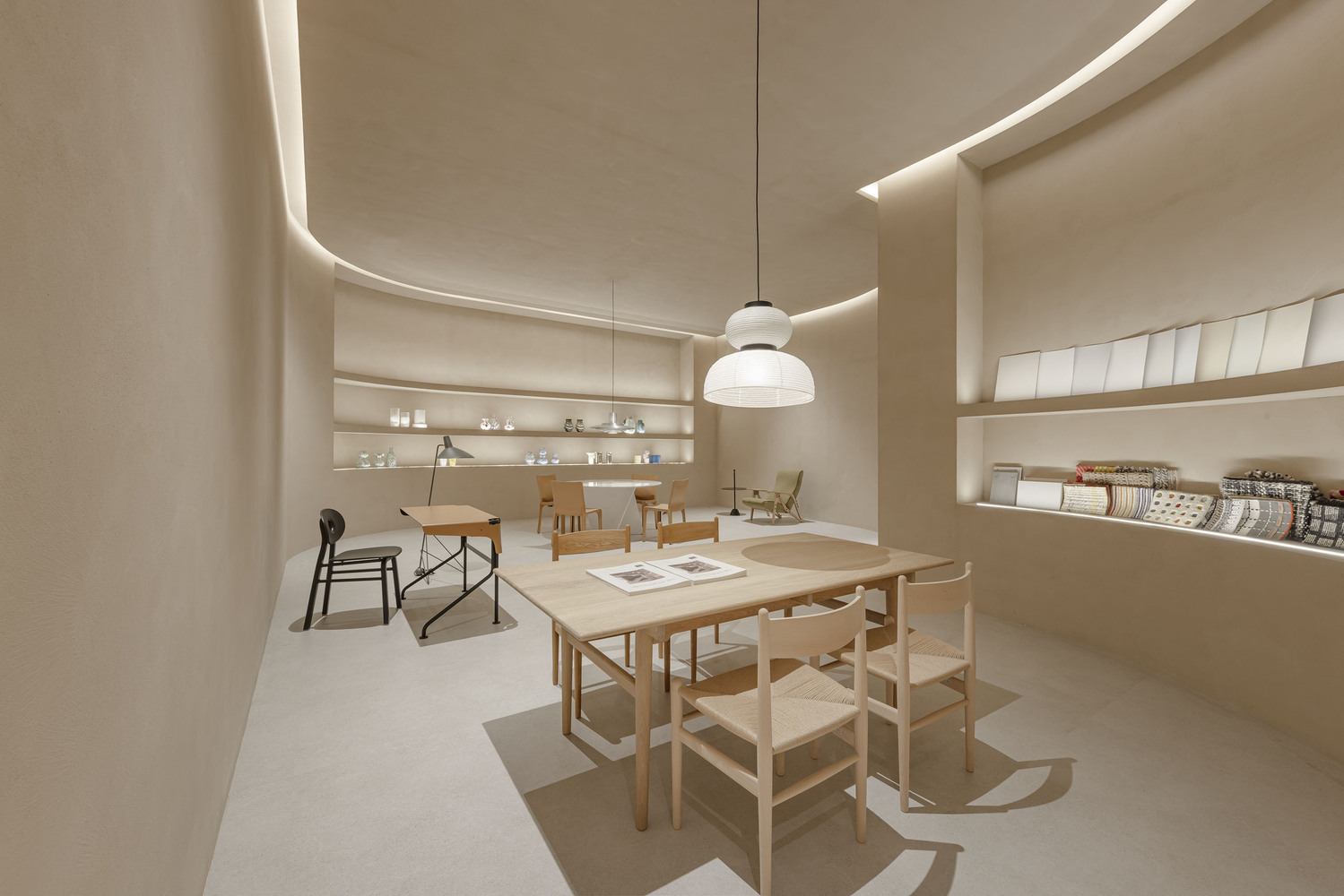 Interior showroom with curved walls, recessed lighting and wooden furniture on pale floor