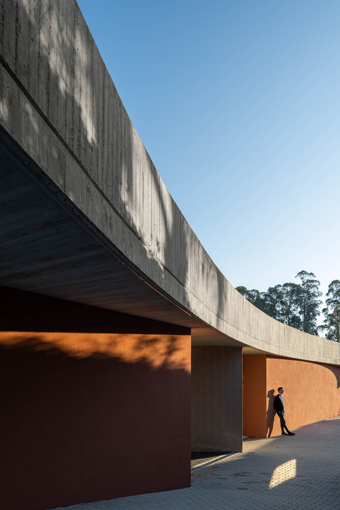 Concrete overhang with board-formed soffit above orange stucco walls and a figure in late afternoon light