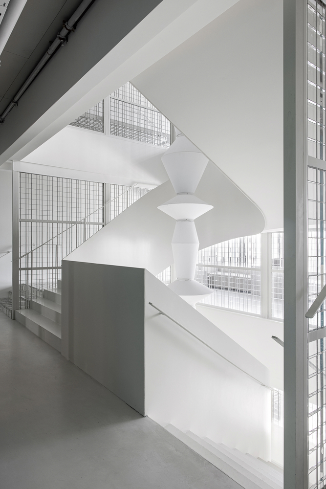 Double-height atrium with helical white staircase and glass block walls filtering daylight