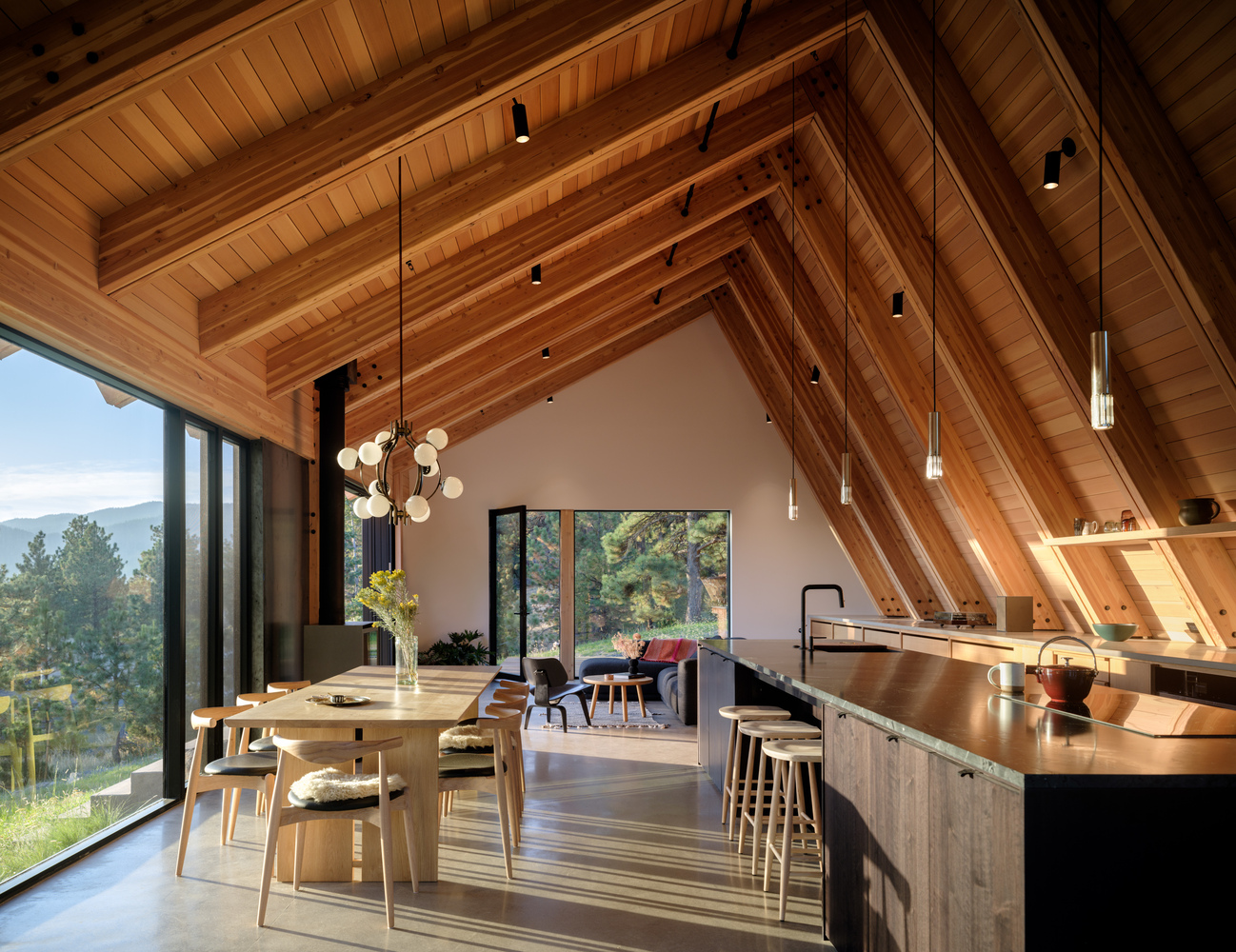 Open kitchen and dining area with exposed timber beams and vaulted ceiling under pendant lighting
