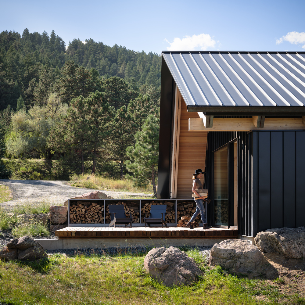 Timber deck terrace with firewood storage wall and figure walking past sliding glass doors