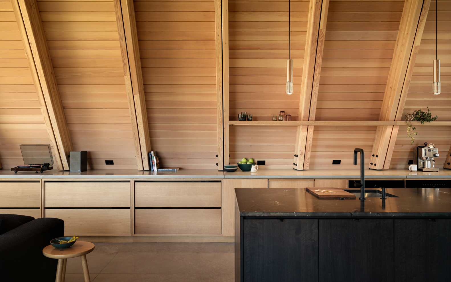 Kitchen cabinetry detail with timber shelving recessed into the sloped ceiling structure at evening