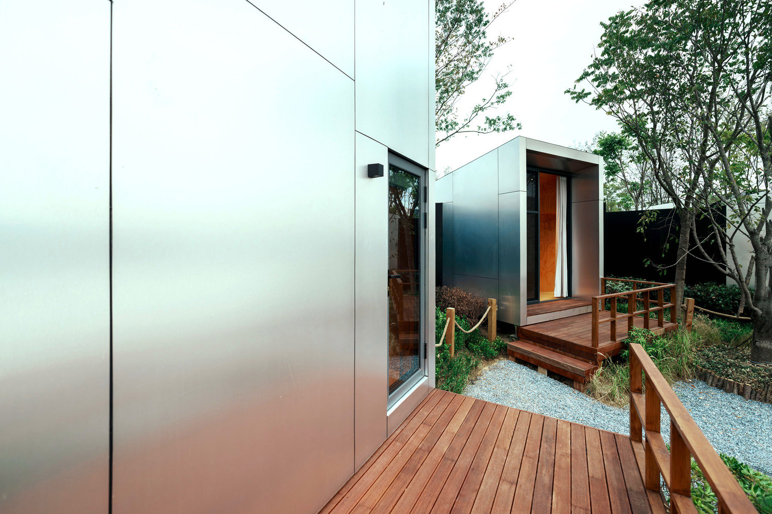Timber deck connecting metal-clad volumes with gravel courtyards and rope railings