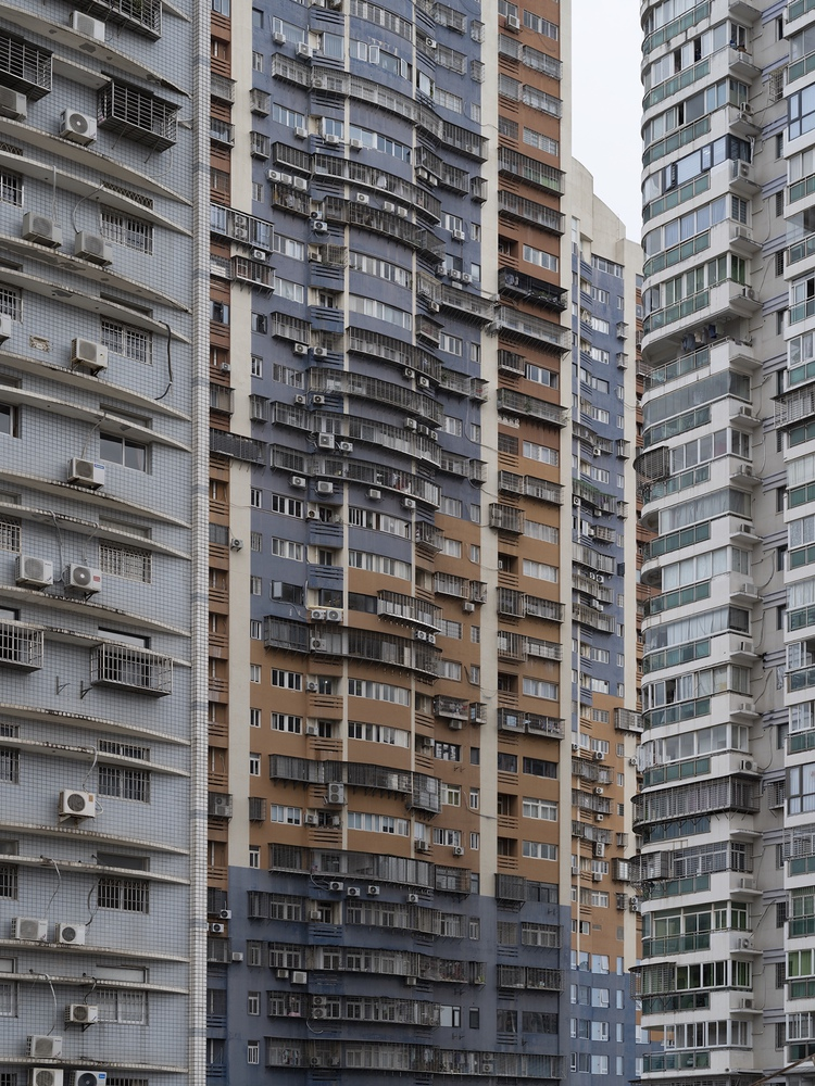 Dense residential tower facades with balconies and air conditioning units in varying shades of grey