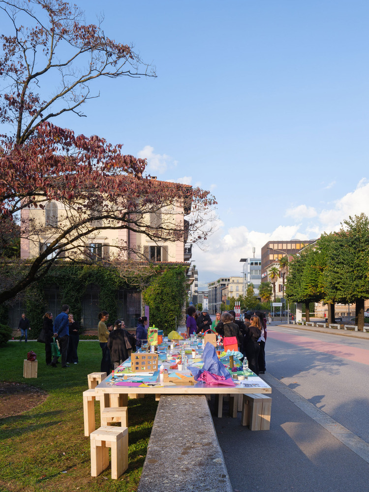 Outdoor workshop table straddling a street edge with participants under late afternoon sky