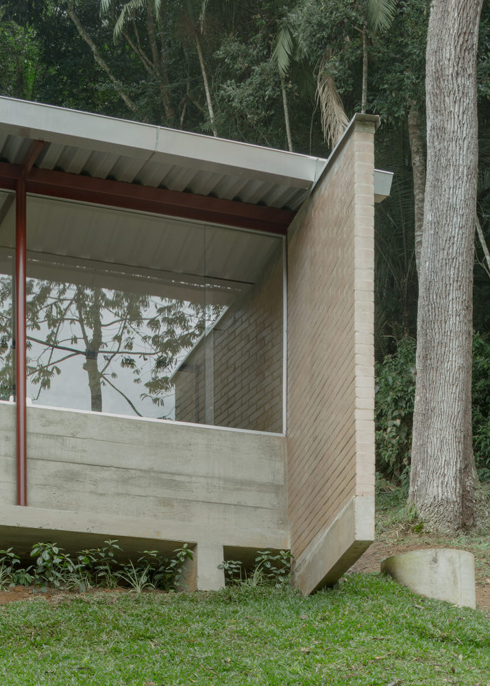 Exterior corner detail showing cantilevered concrete base, buff brick wall and corrugated soffit among palm trees