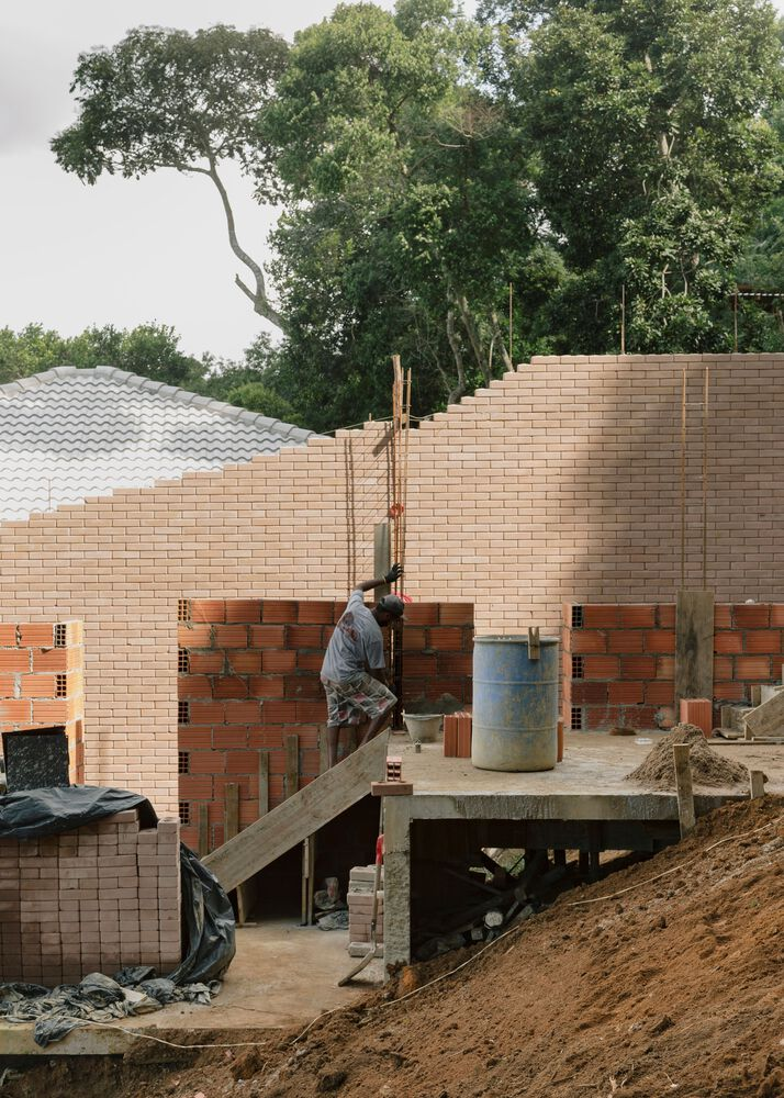 Worker on scaffolding building tan and red brick walls above concrete deck during construction