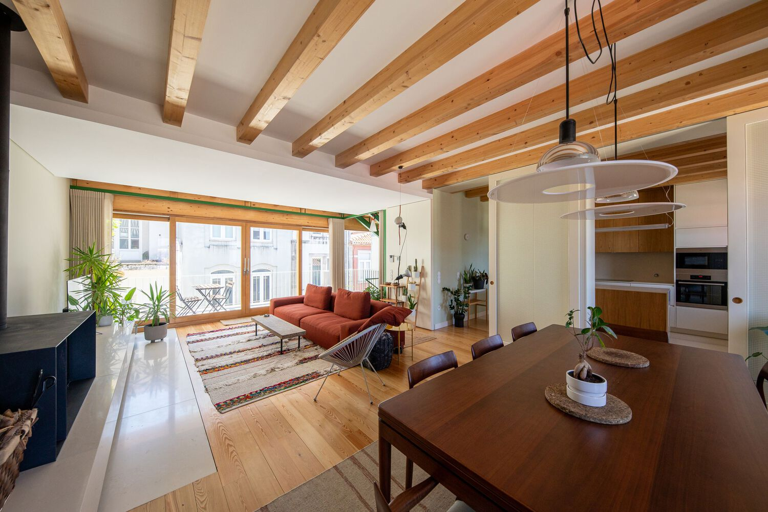 Interior view showing timber ceiling joists above an open living area with large glazed doors