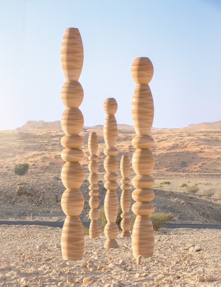 Group of stacked laminated wood columns with spherical and elliptical segments in a desert landscape