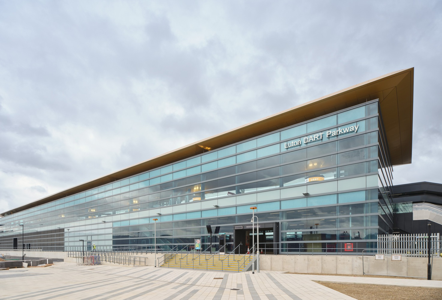 Glass and metal panel facade with cantilevered canopy under overcast sky