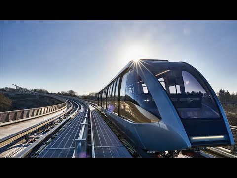 Blue transit train with arched glazed roof on elevated guideway curving into bright sunlight