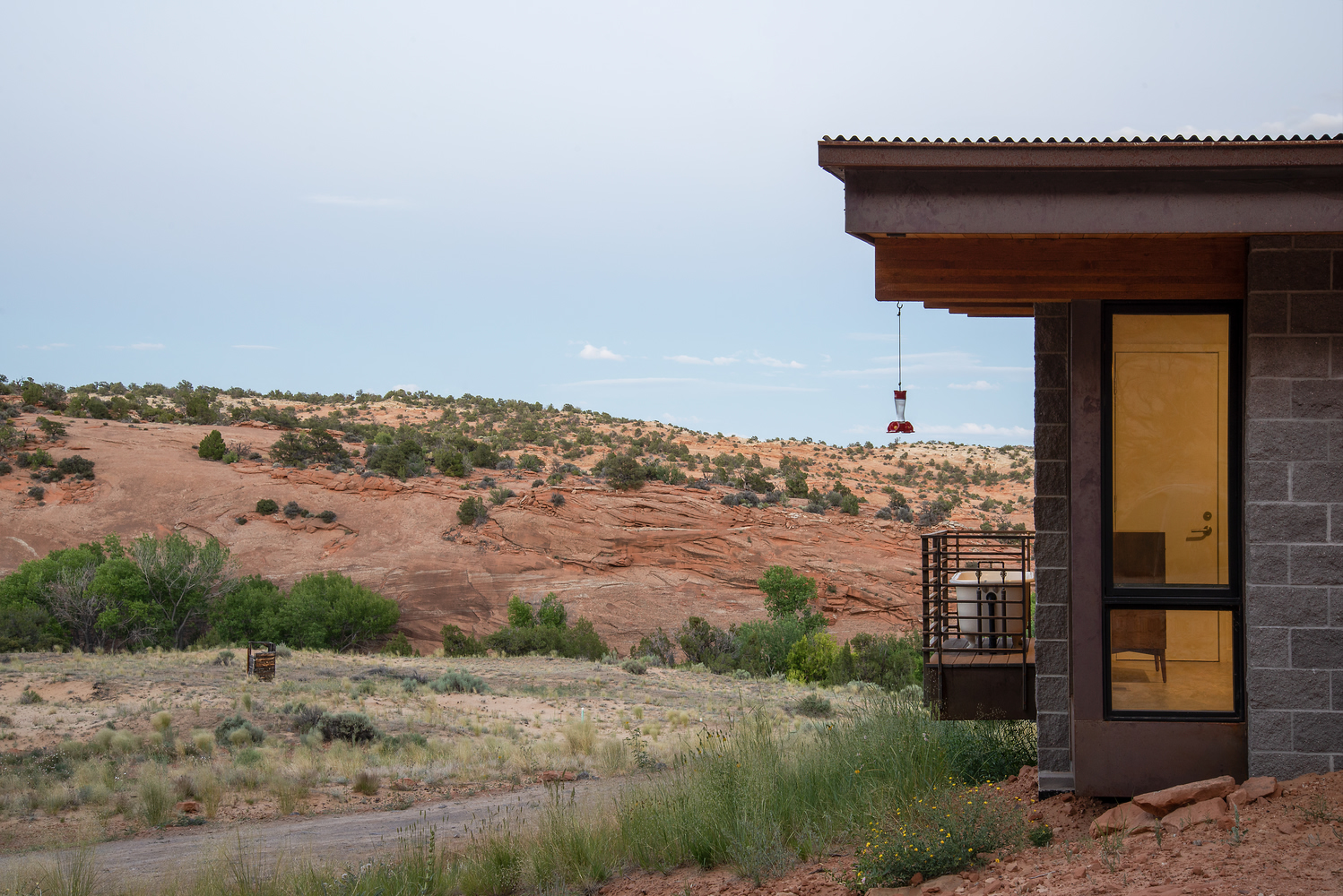 Corner of the concrete block and timber facade with glazed doors opening to the desert landscape