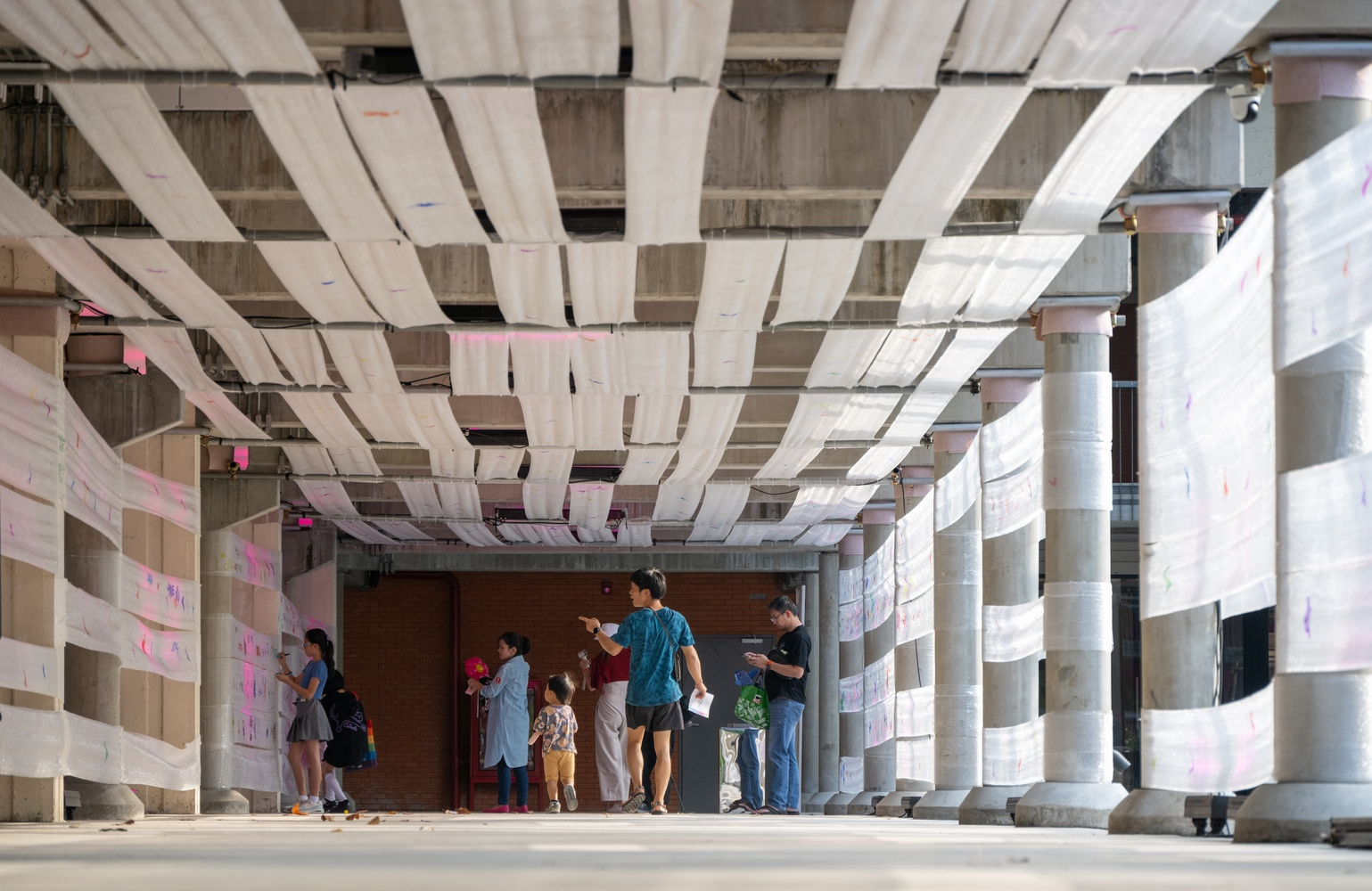Interior corridor with layered horizontal ceiling panels and a group of visitors gathered near a doorway