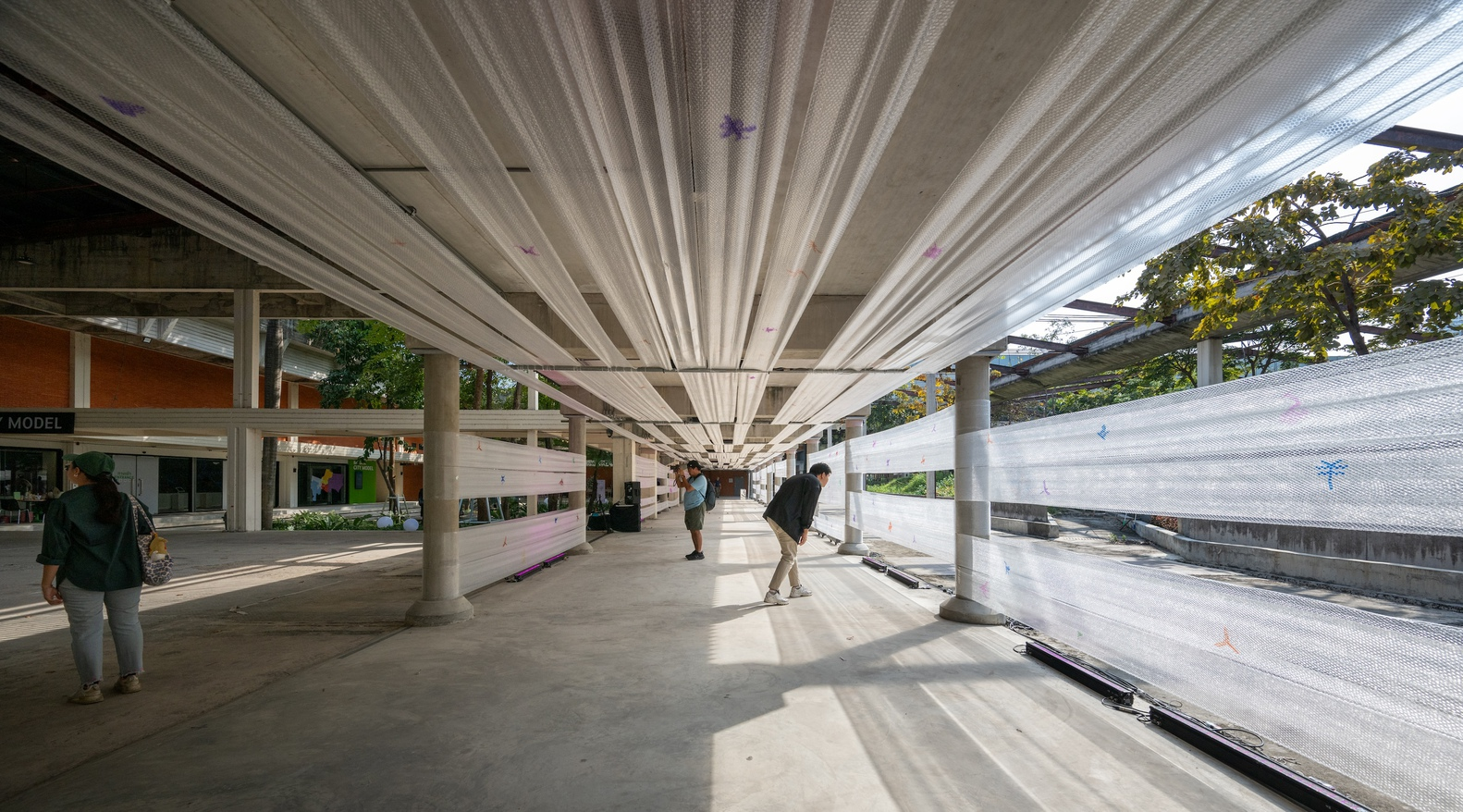 Long view of the pleated ceiling structure converging toward a vanishing point with pedestrians in motion