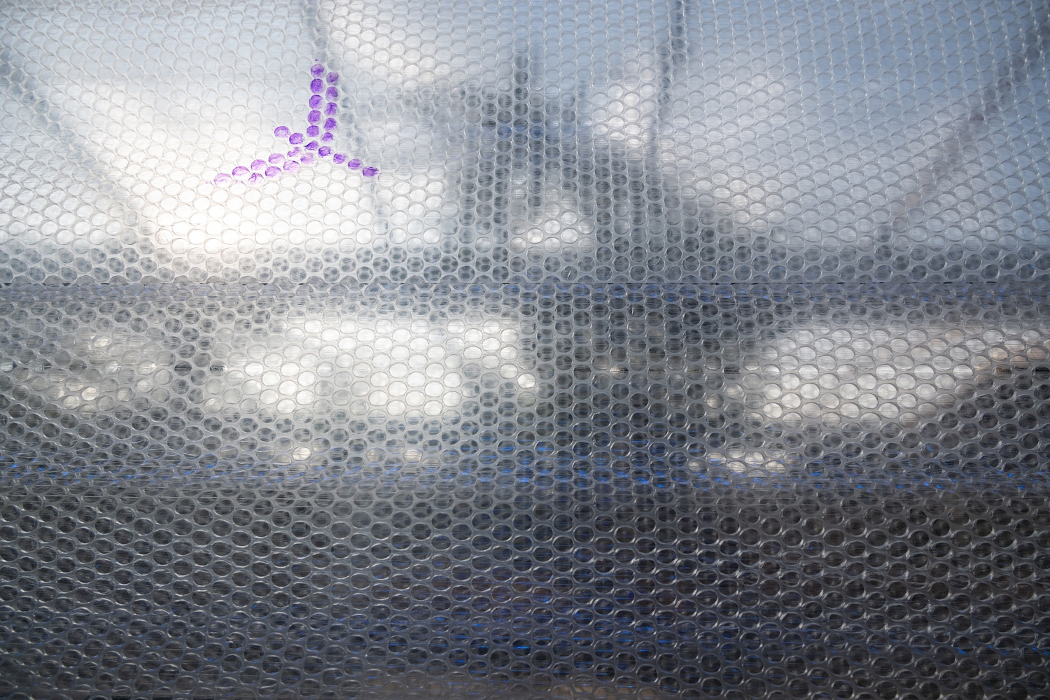 Close-up of translucent hexagonal mesh material with purple graphic pattern through diffused daylight