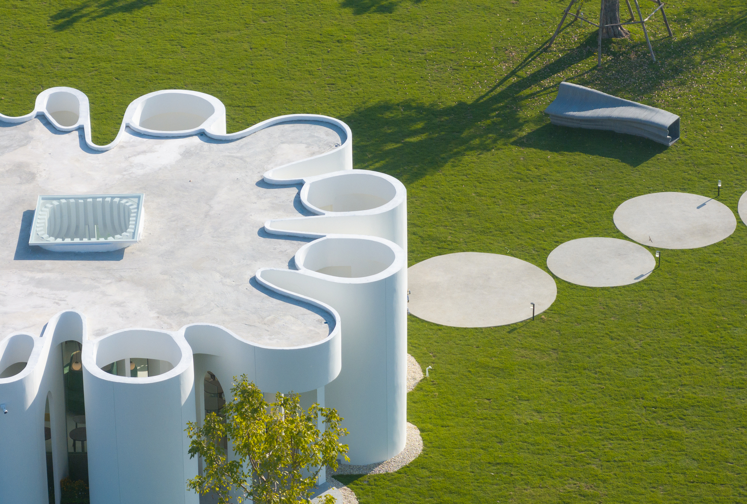 Overhead view showing the scalloped roof edge and circular concrete pads in the lawn