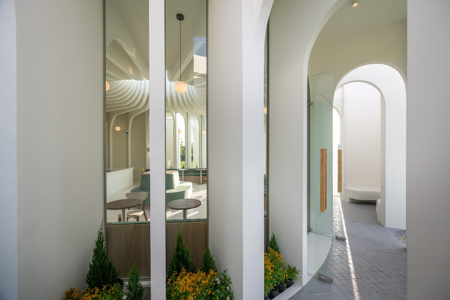Exterior colonnade with planted beds of conifers and yellow flowers between white cylindrical columns