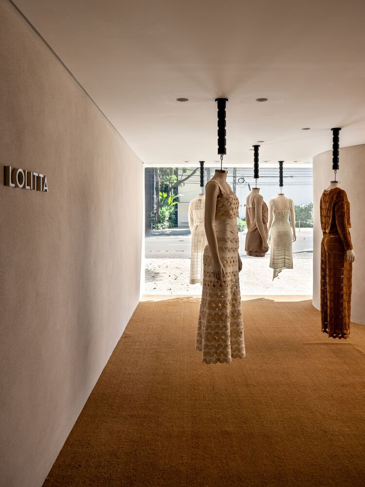 Cork flooring corridor with suspended dress forms on black pendant fixtures facing the glazed entrance