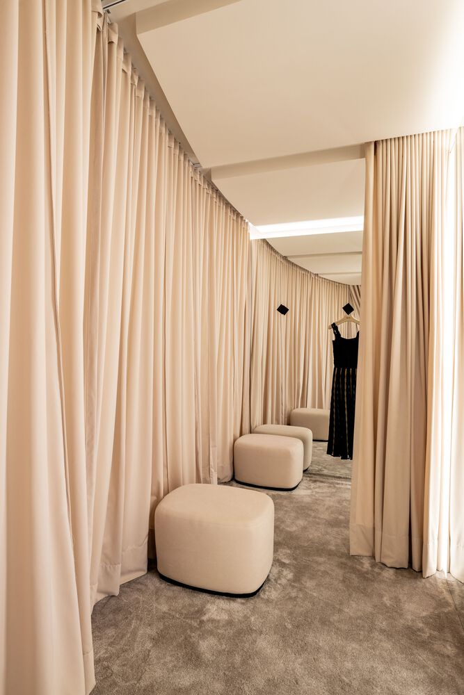 Fitting room corridor with floor-to-ceiling curtains and curved ceiling cove lighting above