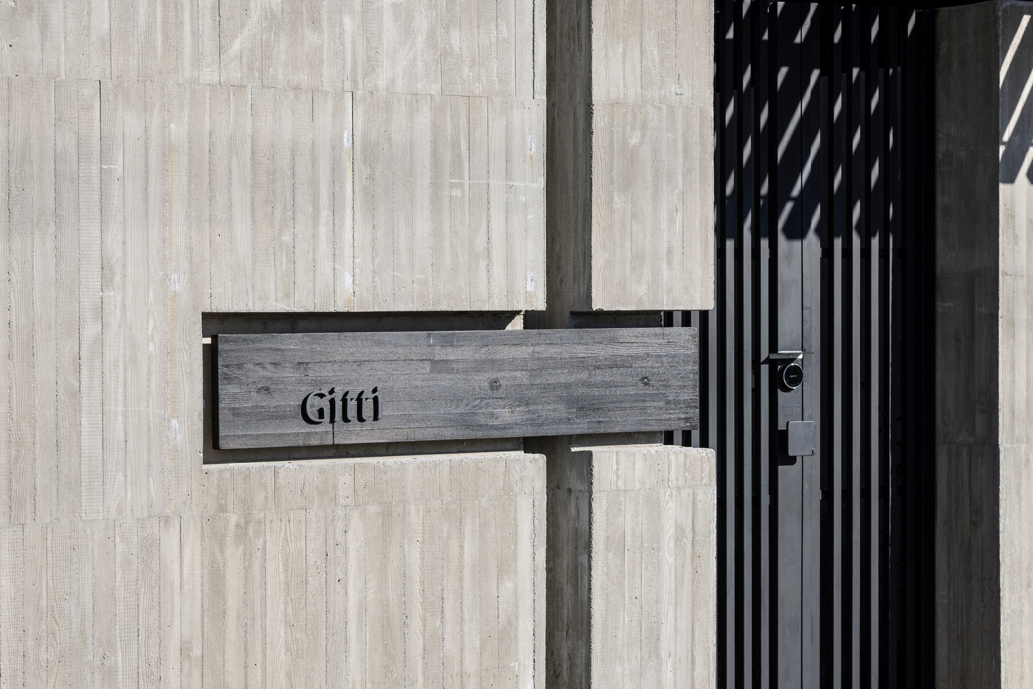 Painted timber mailbox attached to a vertical slatted screen beside a pale timber wall