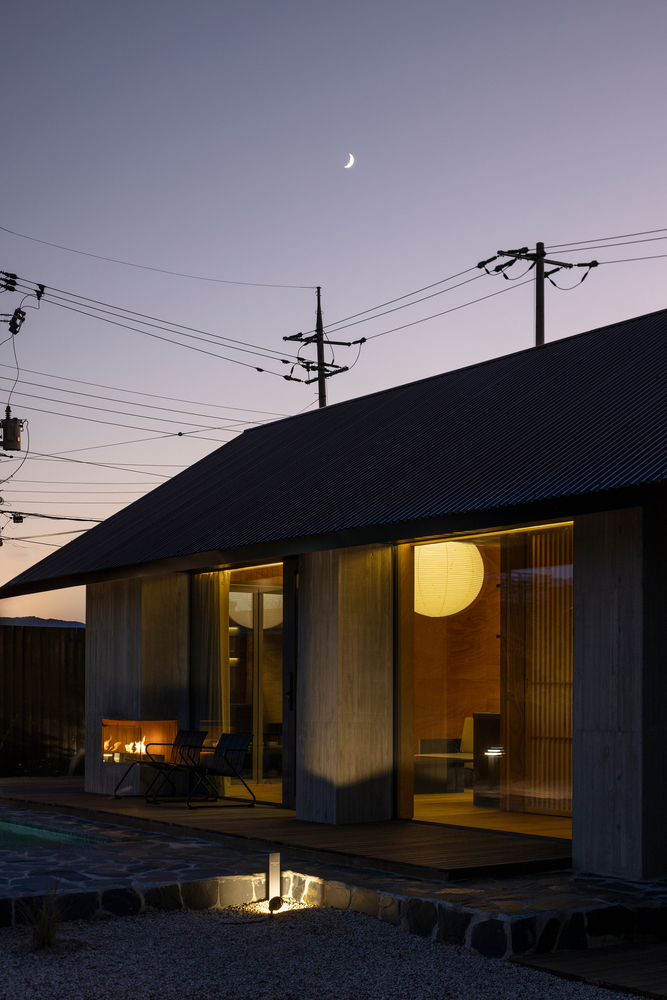 Glazed porch with glowing interior light and crescent moon overhead at dusk