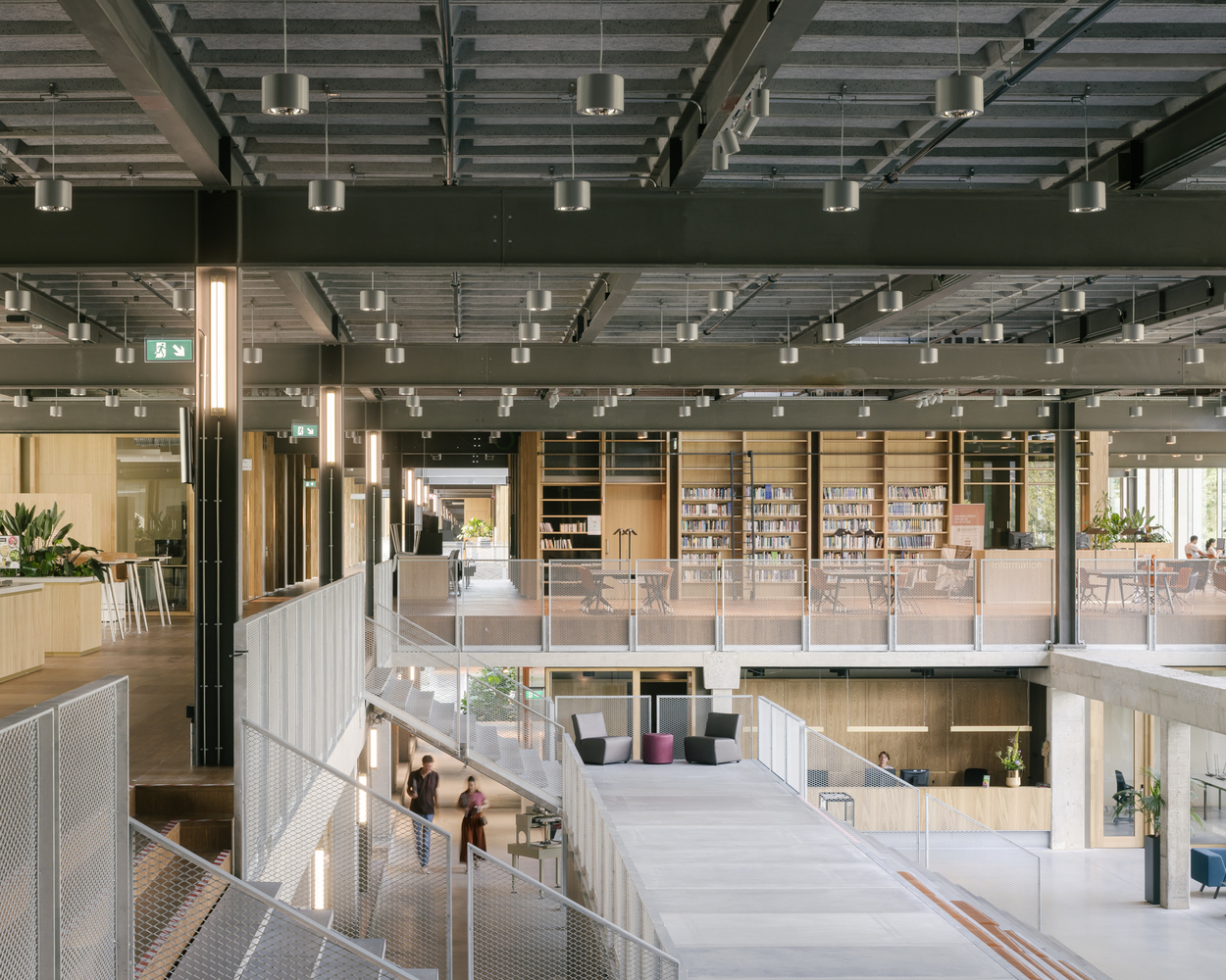 Interior view of multi-level atrium with exposed steel beams, pendant lights and glass-railed mezzanines