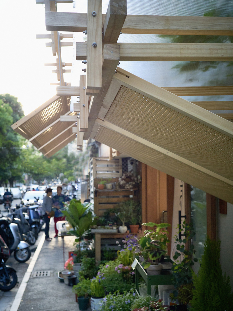 View of the layered timber canopies extending over the planted storefront from the street