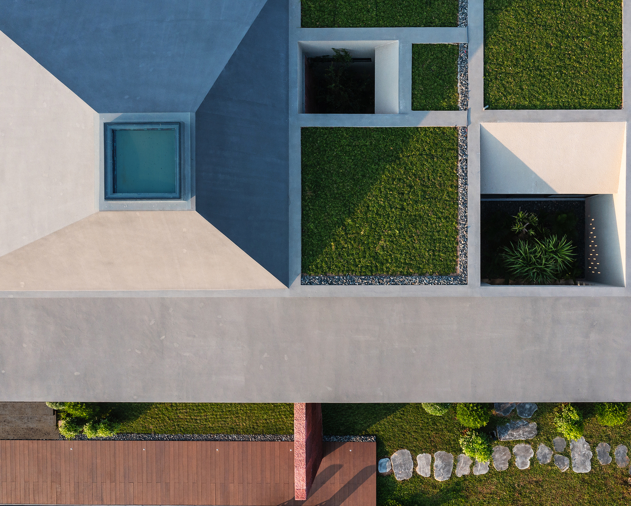 Aerial view showing orthogonal courtyard garden with lawn panels, gravel beds, and planted areas separated by concrete paving