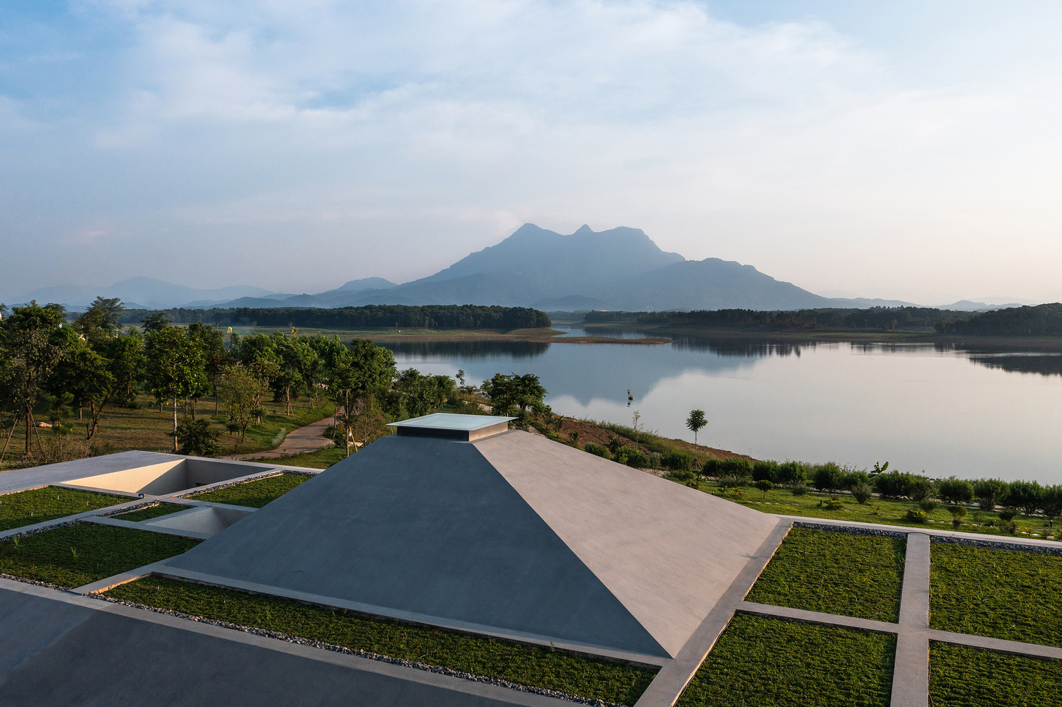 Drone view of the angular roof canopy overlooking a lake and mountain range at dusk