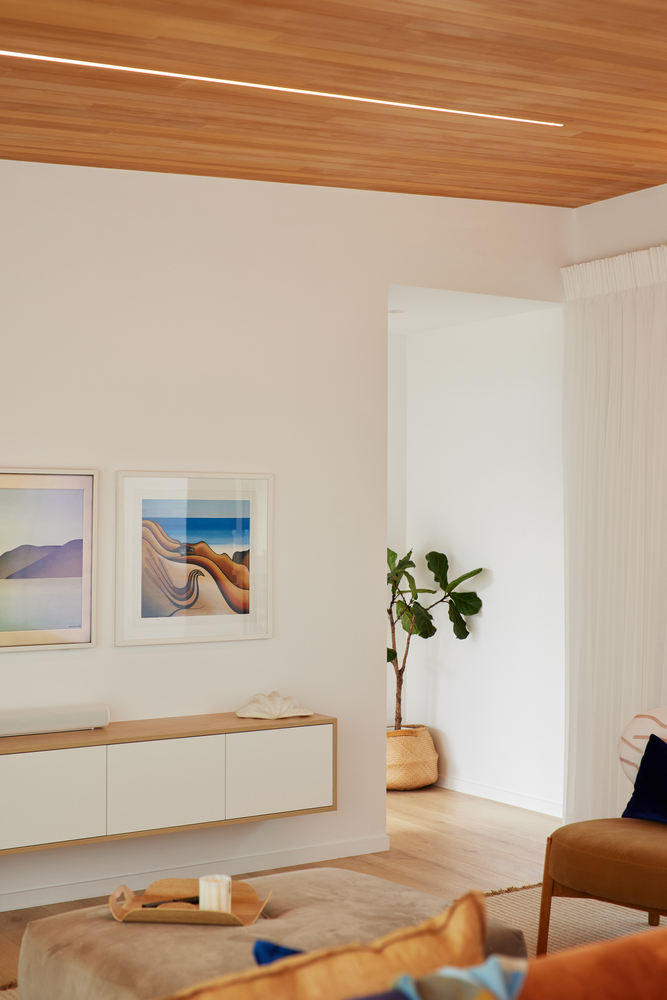 Interior corner with timber ceiling, wall-mounted credenza, potted plant and framed artworks on white walls