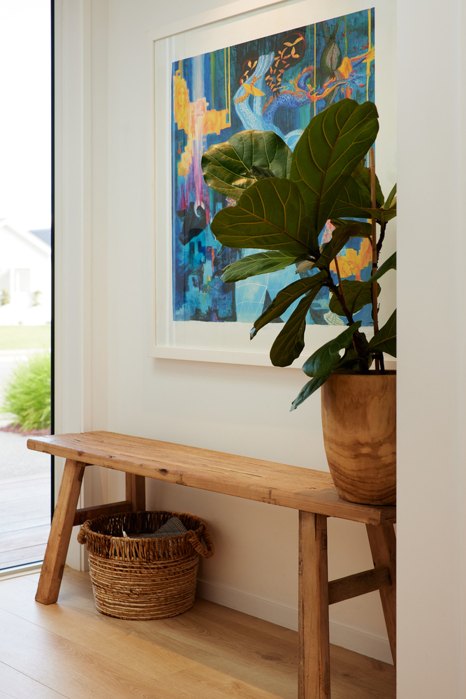 Timber bench with fiddle-leaf fig in terracotta pot and woven basket below a framed artwork