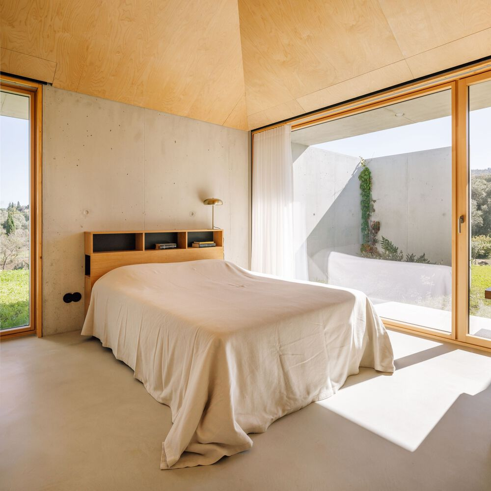 Bedroom with timber-framed glazing opening to a private courtyard with climbing vines