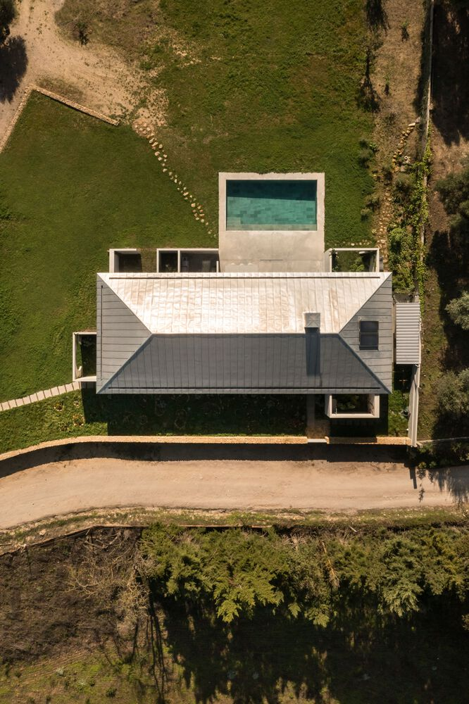 Aerial view of the white horizontal volumes with rooftop pool surrounded by green lawn and trees