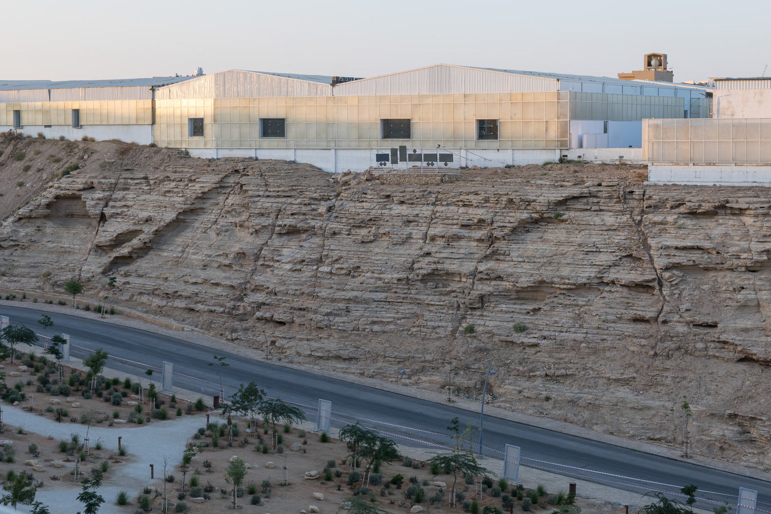 Building atop a sandstone cliff edge above a road lined with newly planted trees