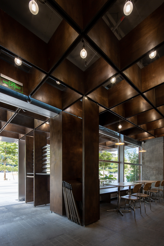 Angular view of the gridded timber ceiling with recessed lighting and steel structural columns below