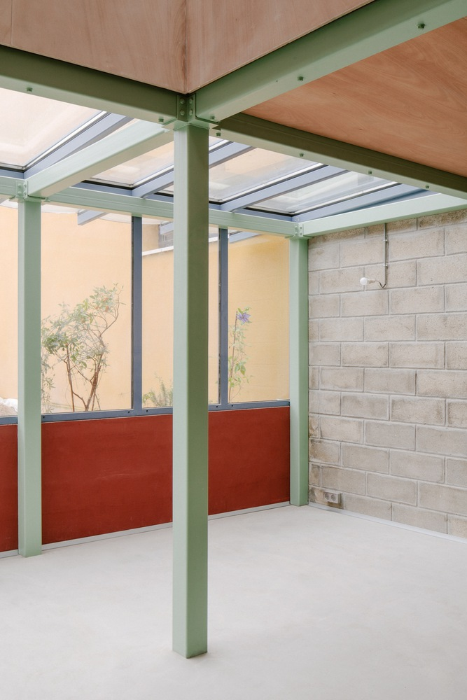 Interior corner showing green steel frame with skylights and red half-height partition wall
