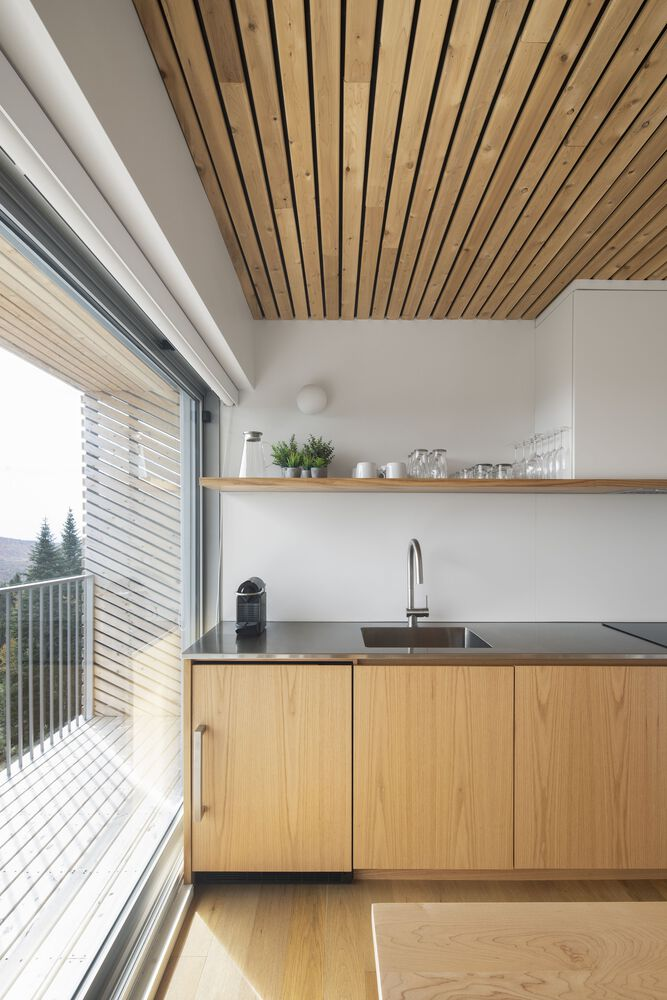 Kitchen counter with light wood cabinetry beneath a slatted ceiling with mountain views beyond