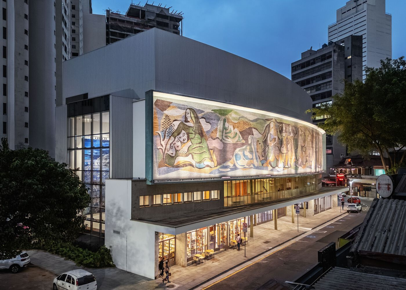 Elevated view of the building at dusk showing the illuminated mosaic facade and surrounding high-rises