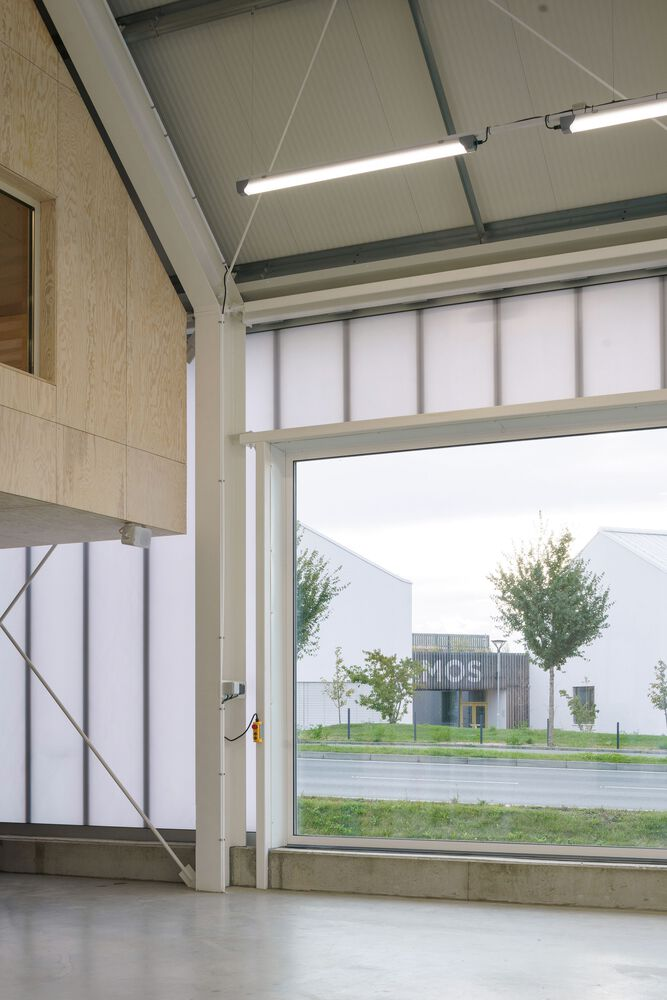 Interior view through a large garage door opening to the street with young trees outside