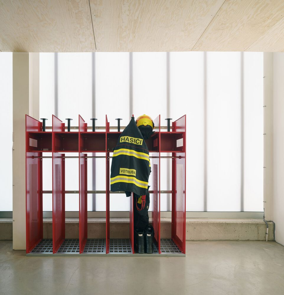 Red metal storage rack with a firefighter climbing beneath a plywood ceiling in diffused daylight