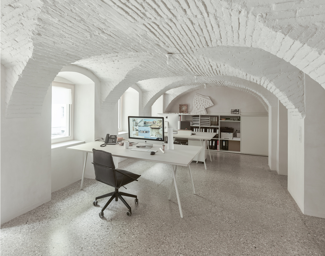 White vaulted brick ceiling with radiating ribs above an office workspace with terrazzo flooring