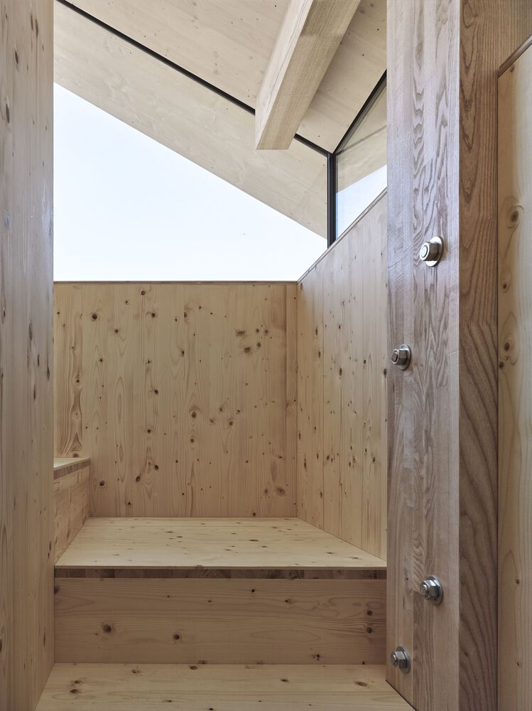 Narrow timber stairwell with angled clerestory windows illuminating the knotted wood surfaces